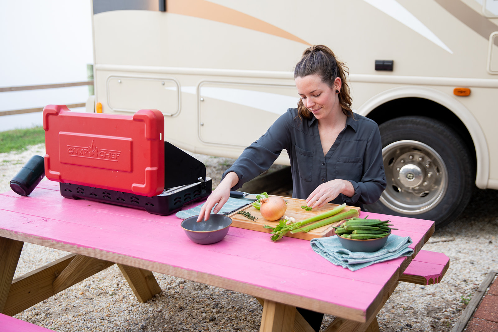 Aubrey prepping vegetables outside at a hot pink picnic table.
