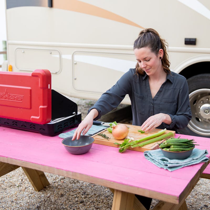 Aubrey prepping vegetables outside at a hot pink picnic table.