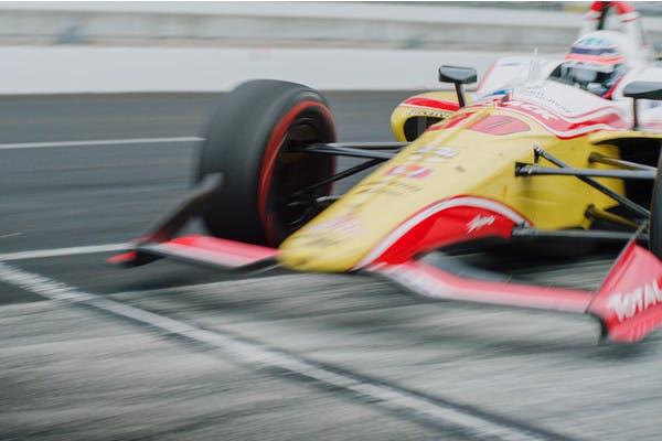 Takuma Sato's race car zooms down the Indy 500 track.