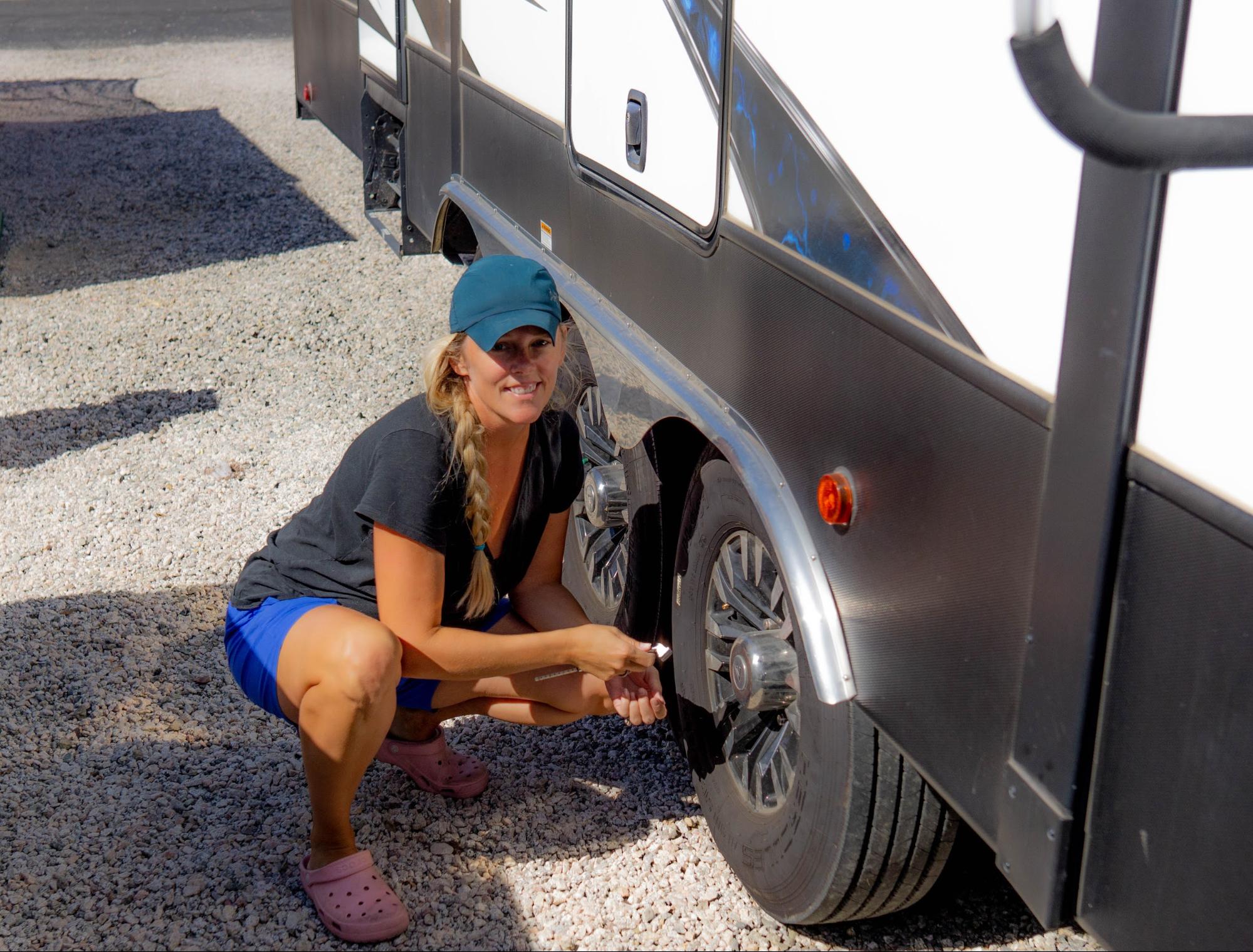 Samantha squats by the tire of her Dutchmen Voltage.