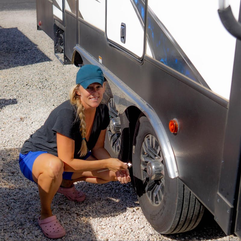 Samantha squats by the tire of her Dutchmen Voltage.