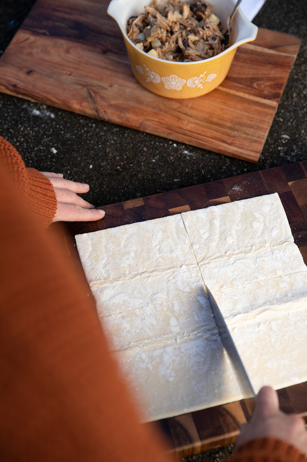 Cutting pastry dough into equal squares on a cutting board.