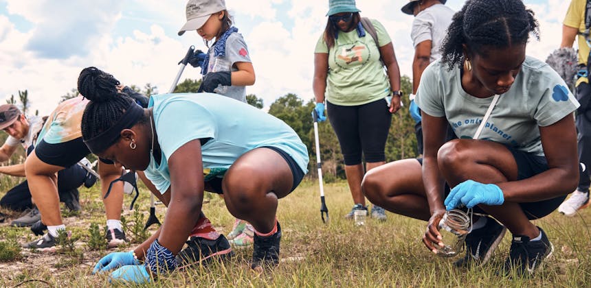 Girl Scouts bent over picking up trash in a park
