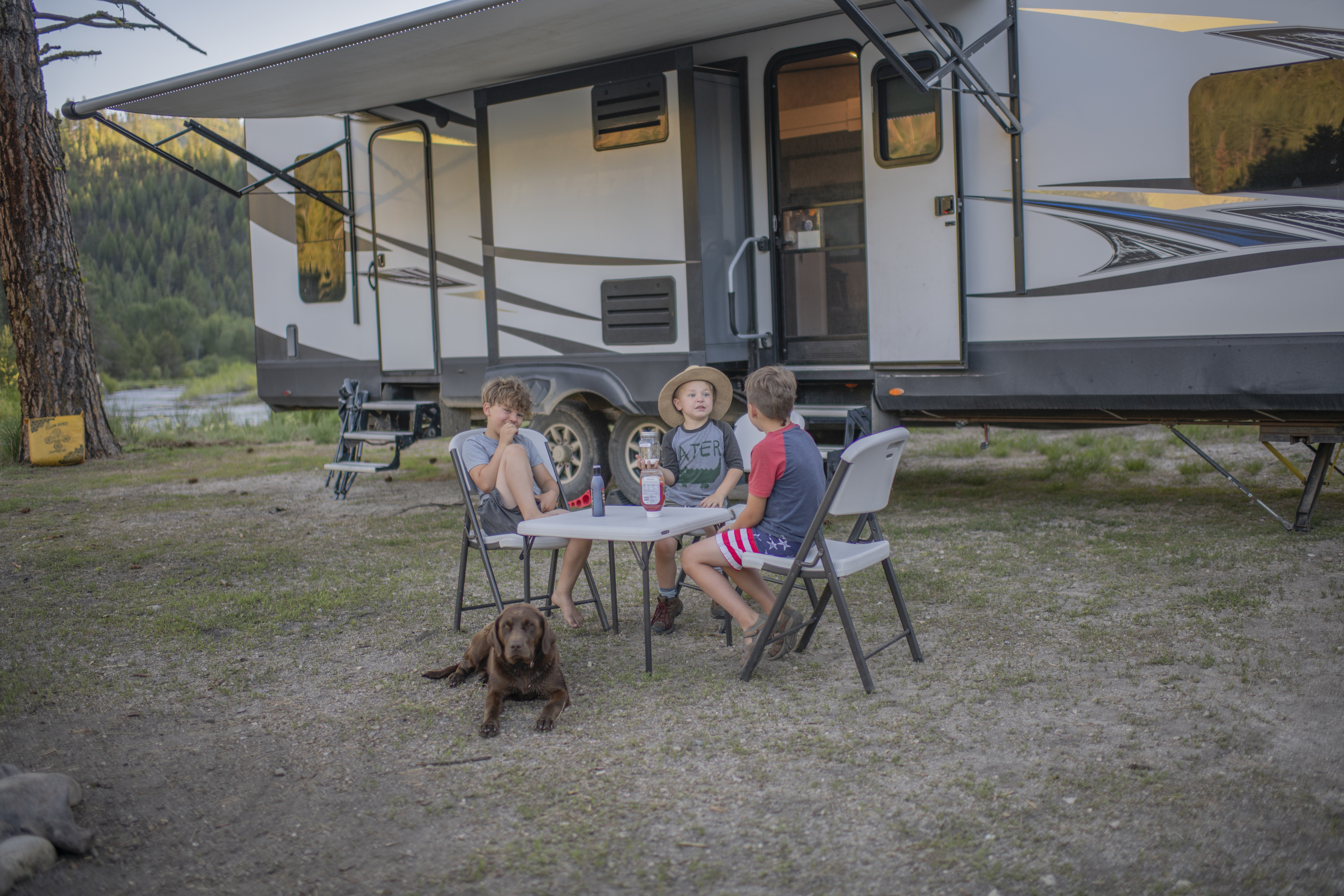 Chelsea Day's children sitting outside at a folding table in front of her Highland Ridge RV.