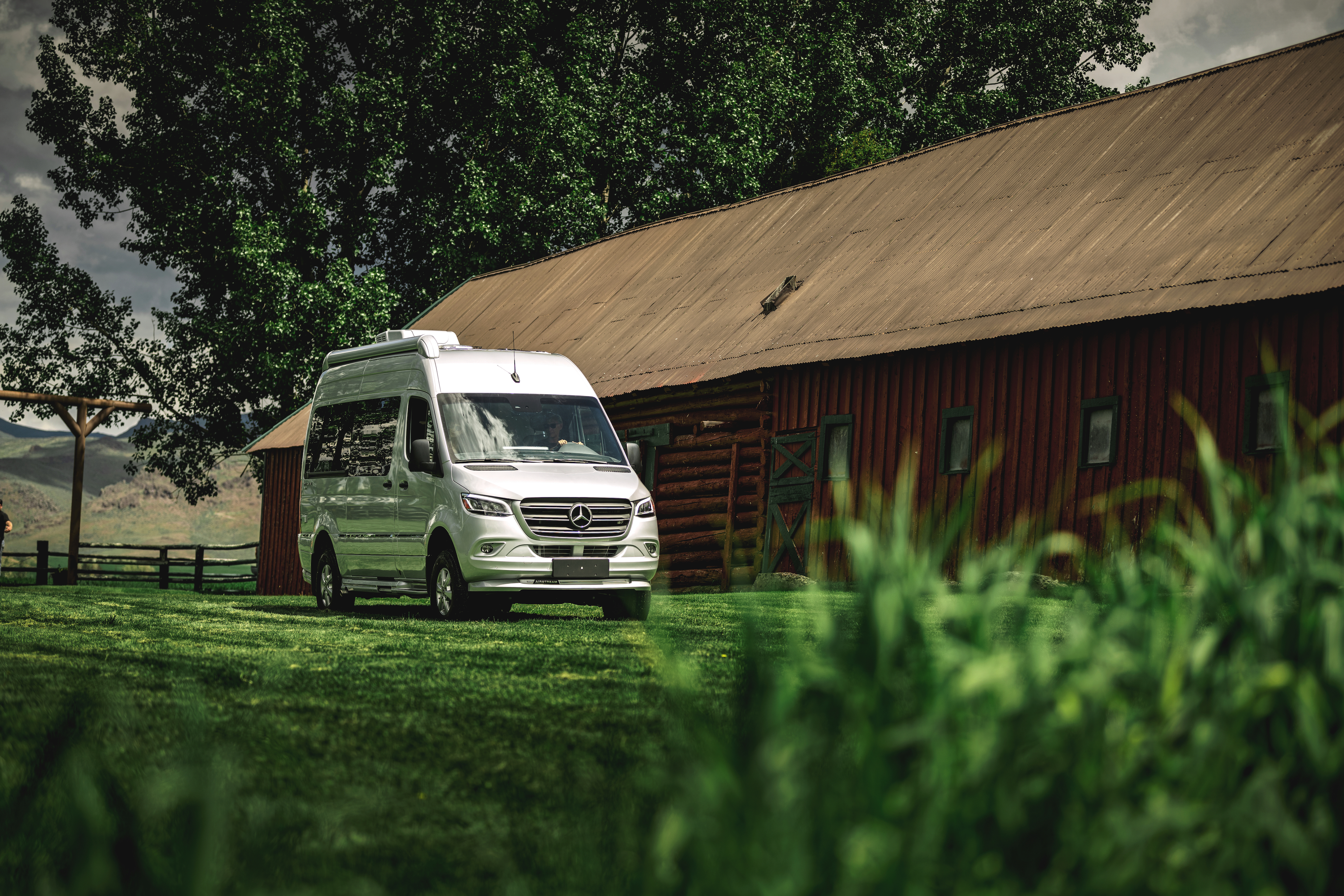 An airstream interstate class b camper van pulling up next to a barn 