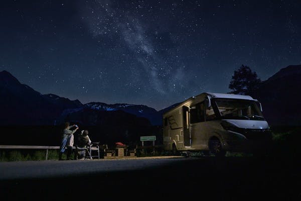 Family stargazes in the mountains of Austria next to their Class B RV from Hymer.