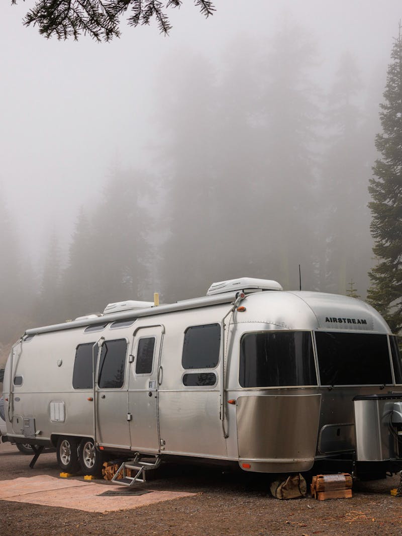 Karen and Lenny Blue's Airstream Flying Cloud travel trailer parked at a campsite in the foggy woods.