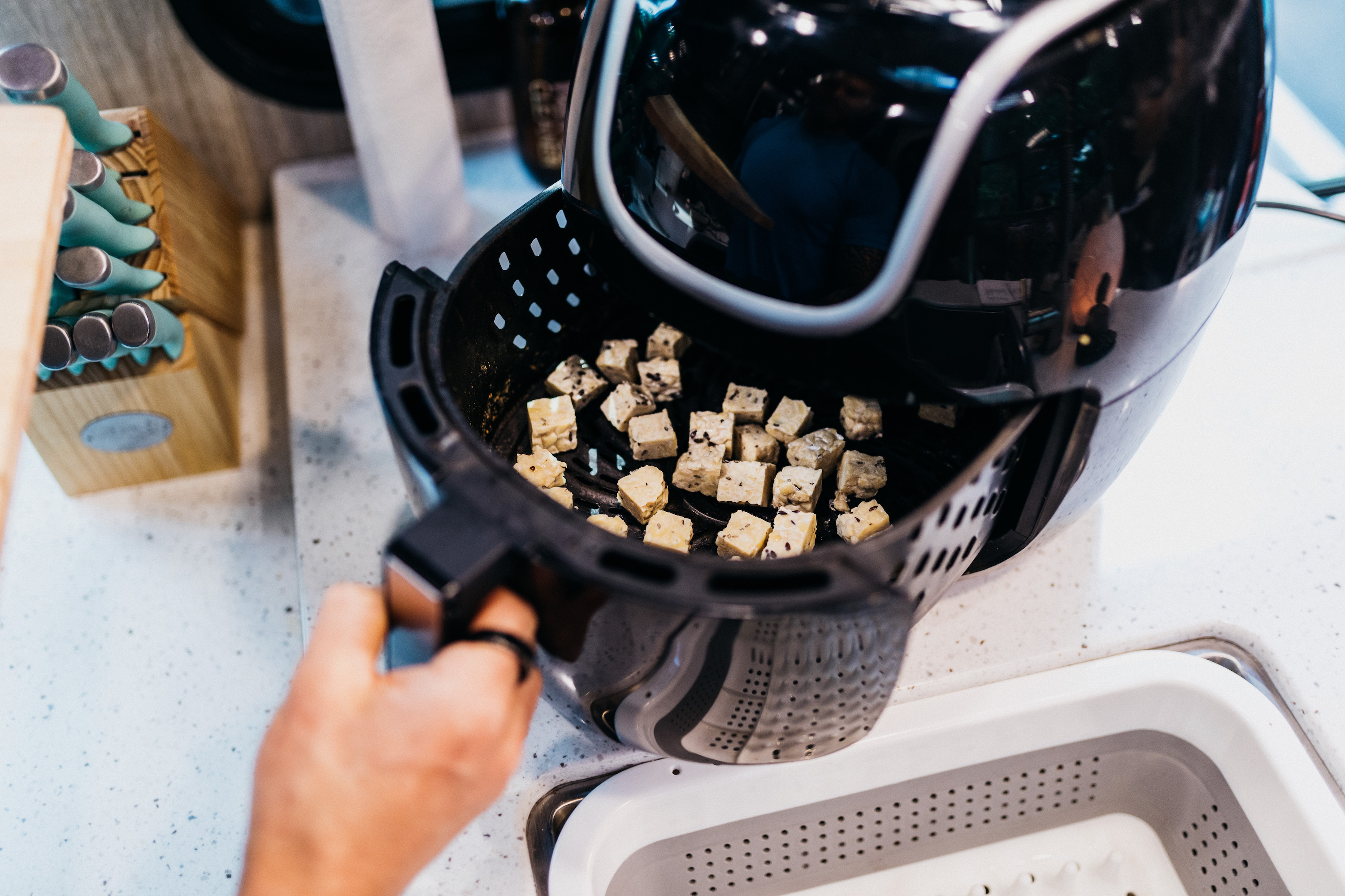 Crispy tofu cubes in the basket of an air fryer. 
