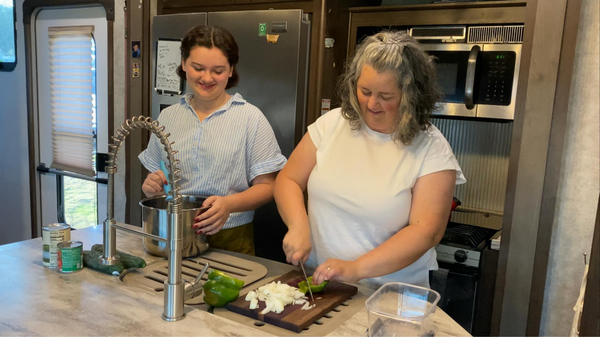 Mother and daughter chop vegetables inside RV at kitchen counter