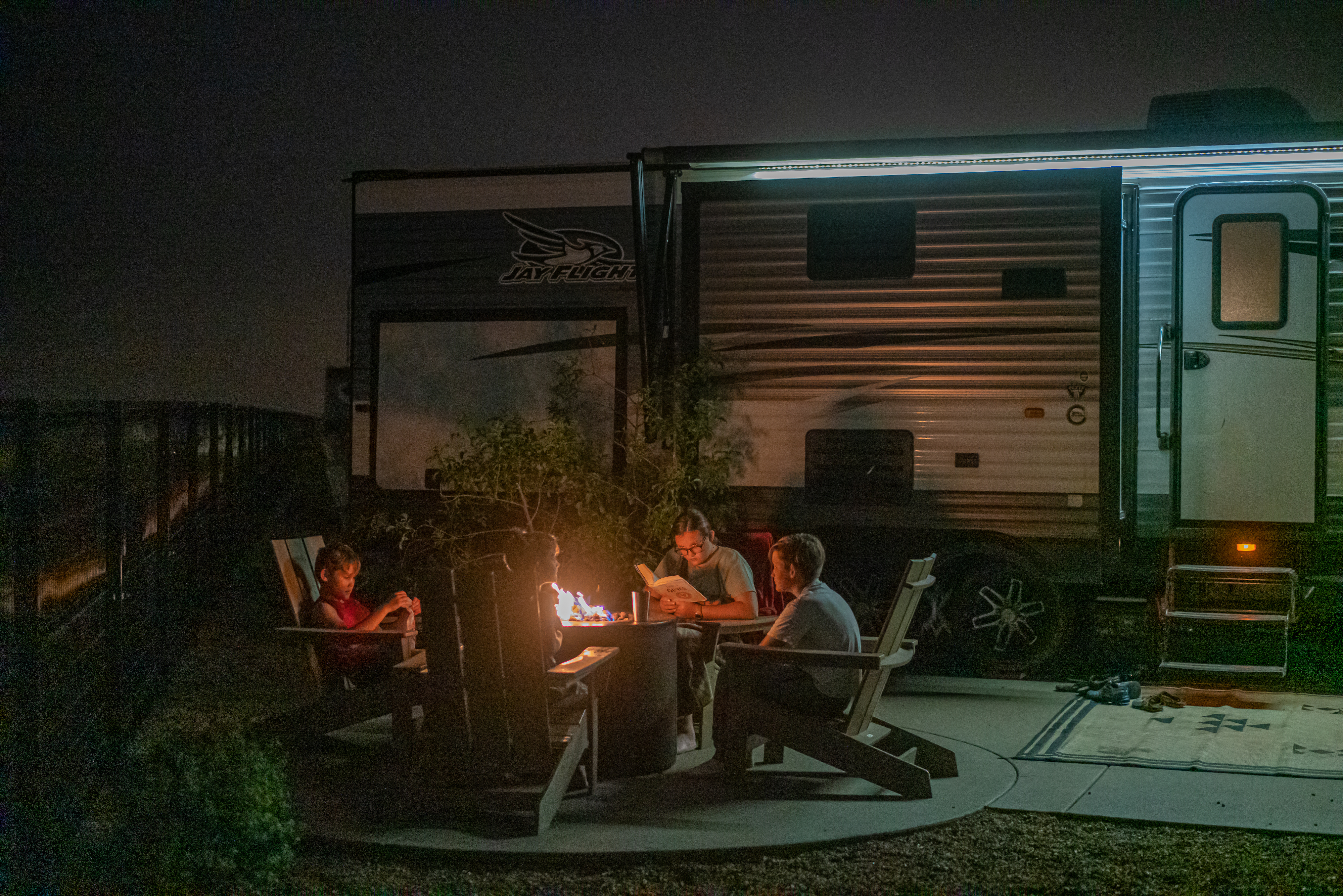 Renee Tilby's family hanging out around a campfire at night in front of their RV