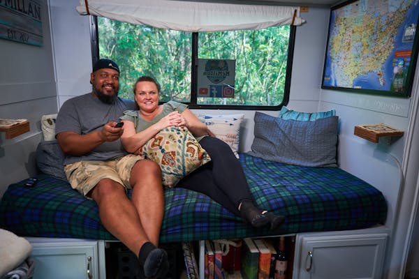 Ben and Christina McMillan lounging inside their RV watching TV