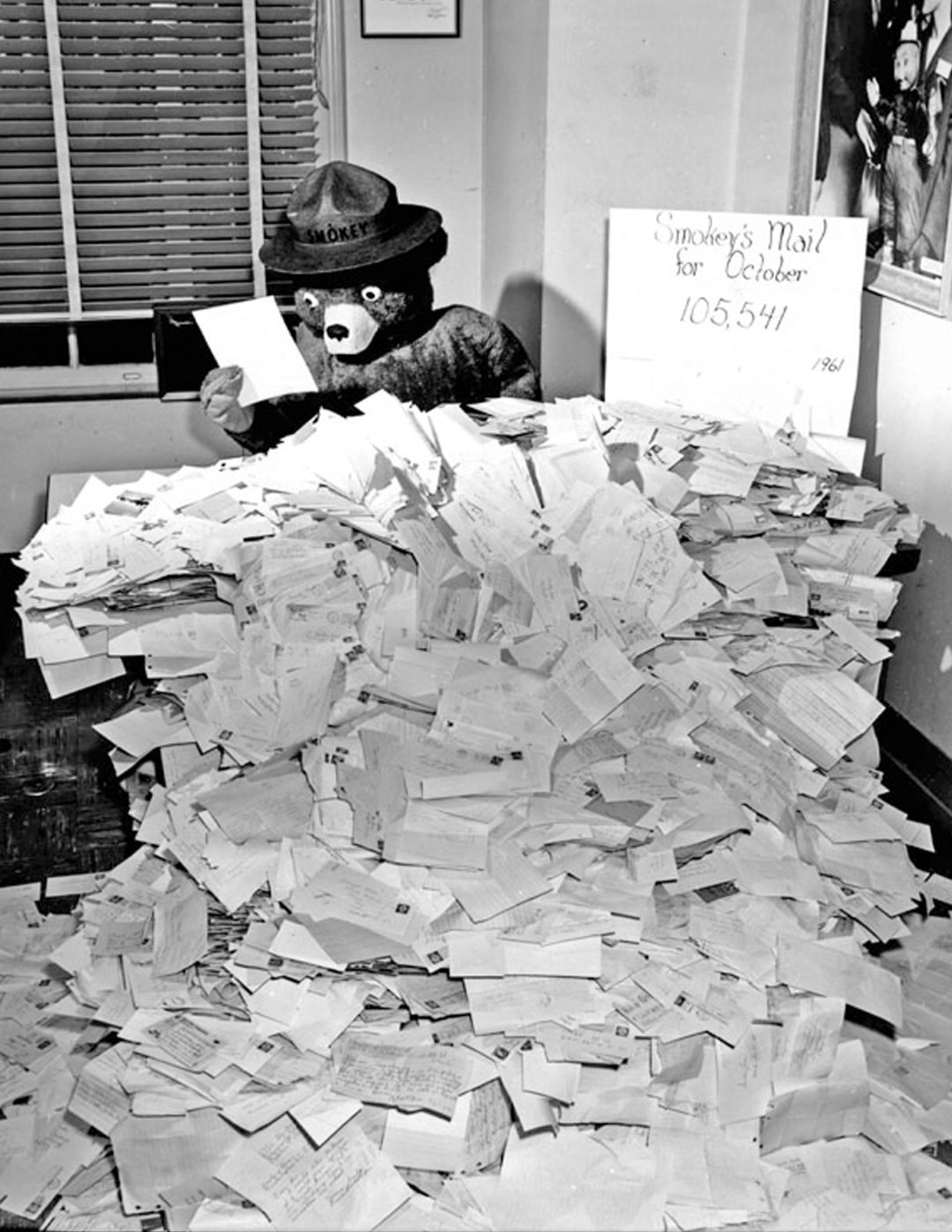 Black and white photo of Smokey Bear reading fan mail