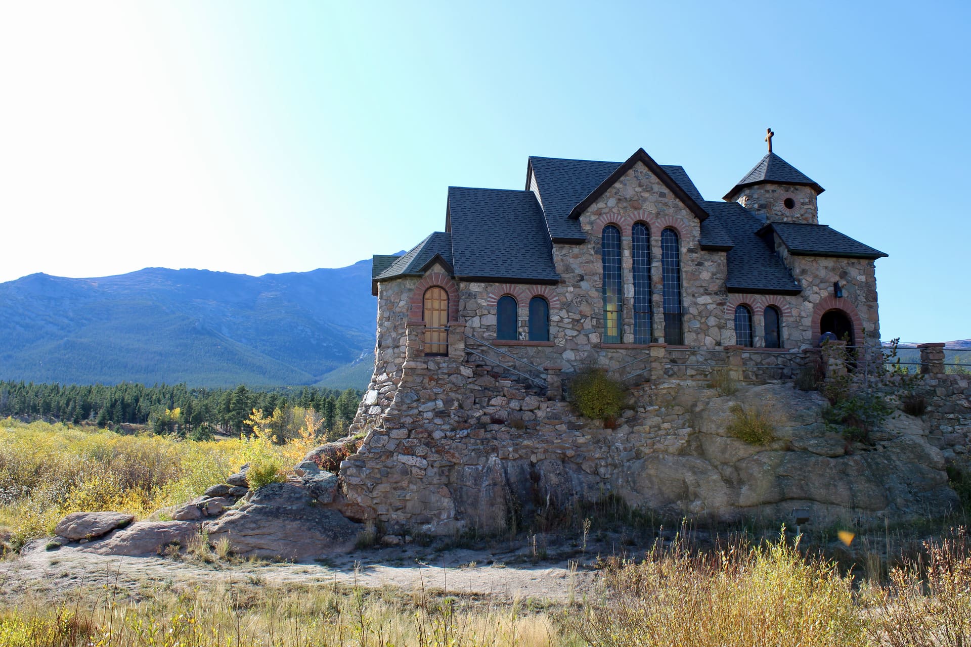 Stone church in the middle of a grassy field surrounded by mountains