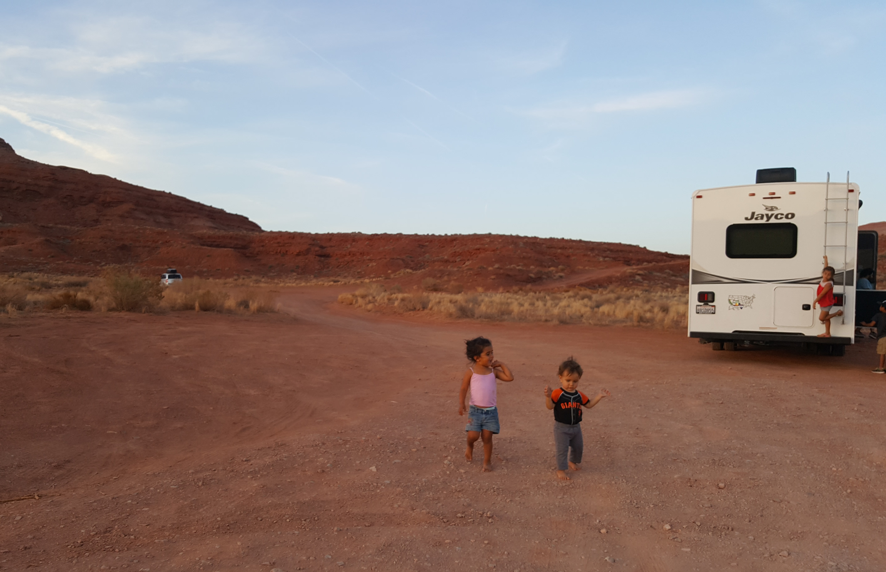 Sandra Peña's kids run around outside on a dirt road in front of her Jayco Class C RV. 