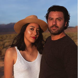 Mariela Torres wearing a hat posing with Santi Araujo smiling faintly.