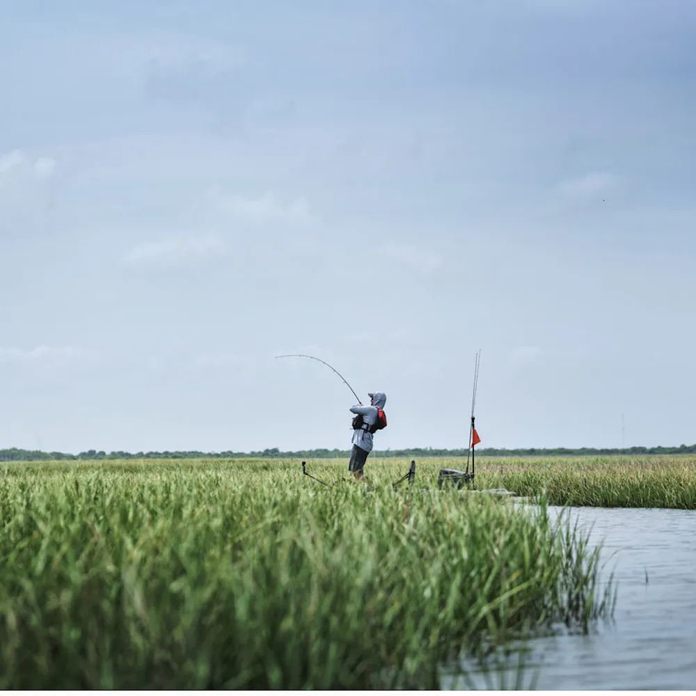 Robert Field stands on his kayak while fishing. 
