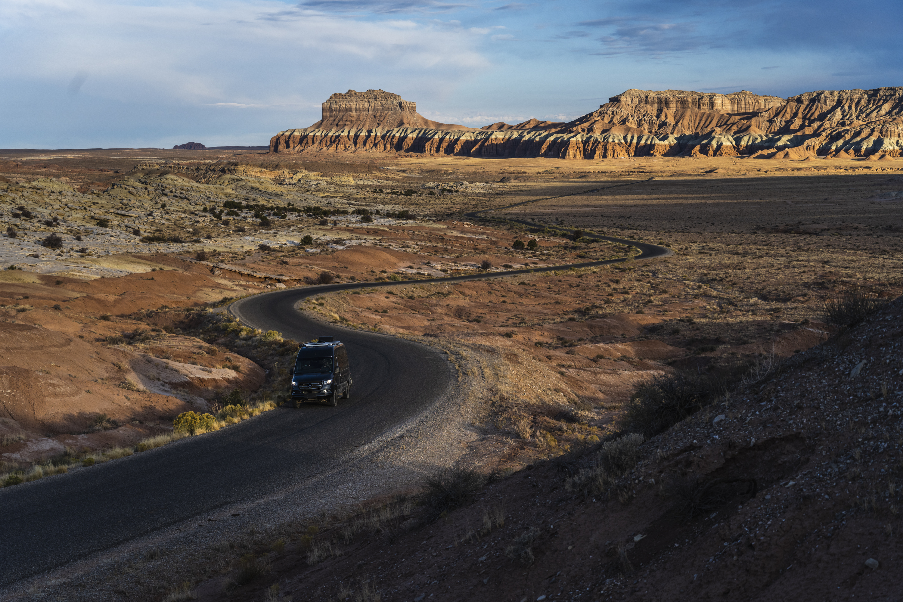 A TMC Sanctuary Class B RV drives down a road in the desert.