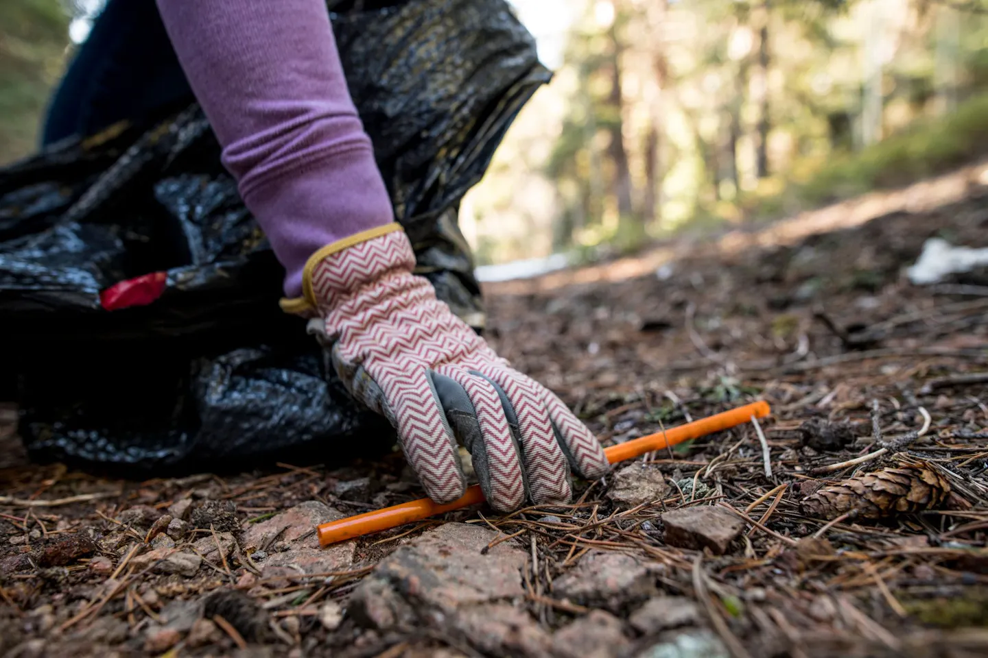A woman picking up a plastic straw outside