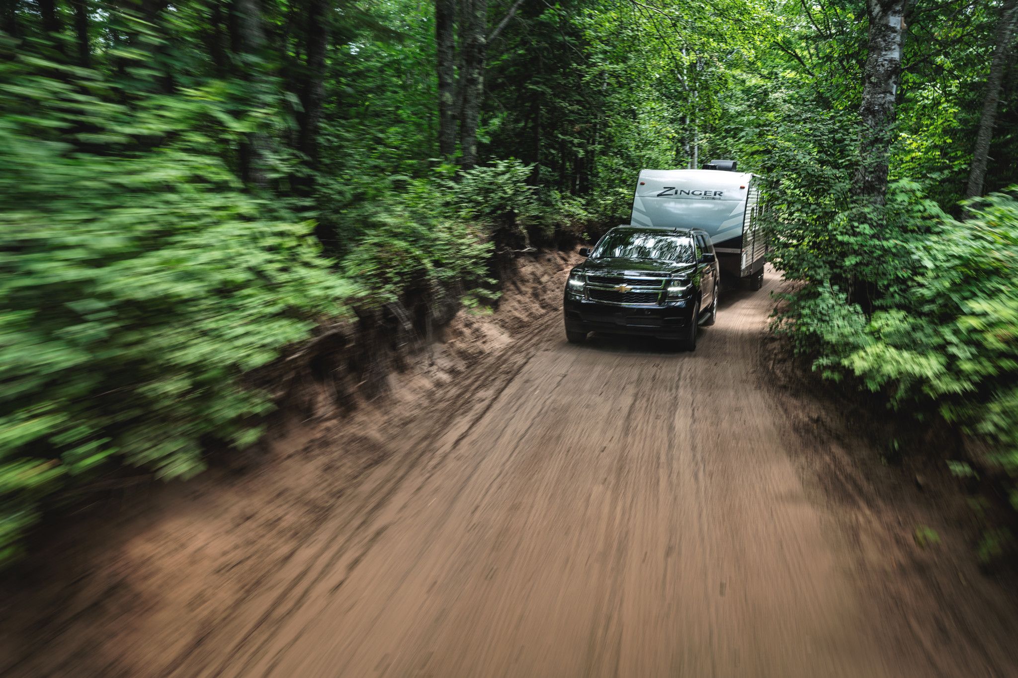 A zinger travel trailer driving through a forrest