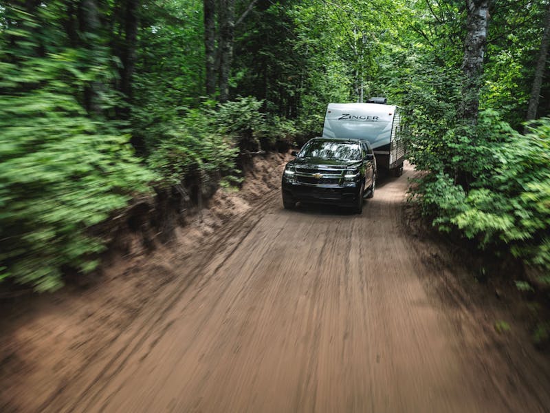 A zinger travel trailer driving through a forrest