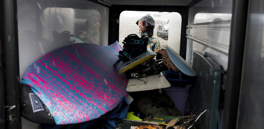 Layla grabbing snowboarding equipment out of the storage in a Tiffin Wayfarer RV