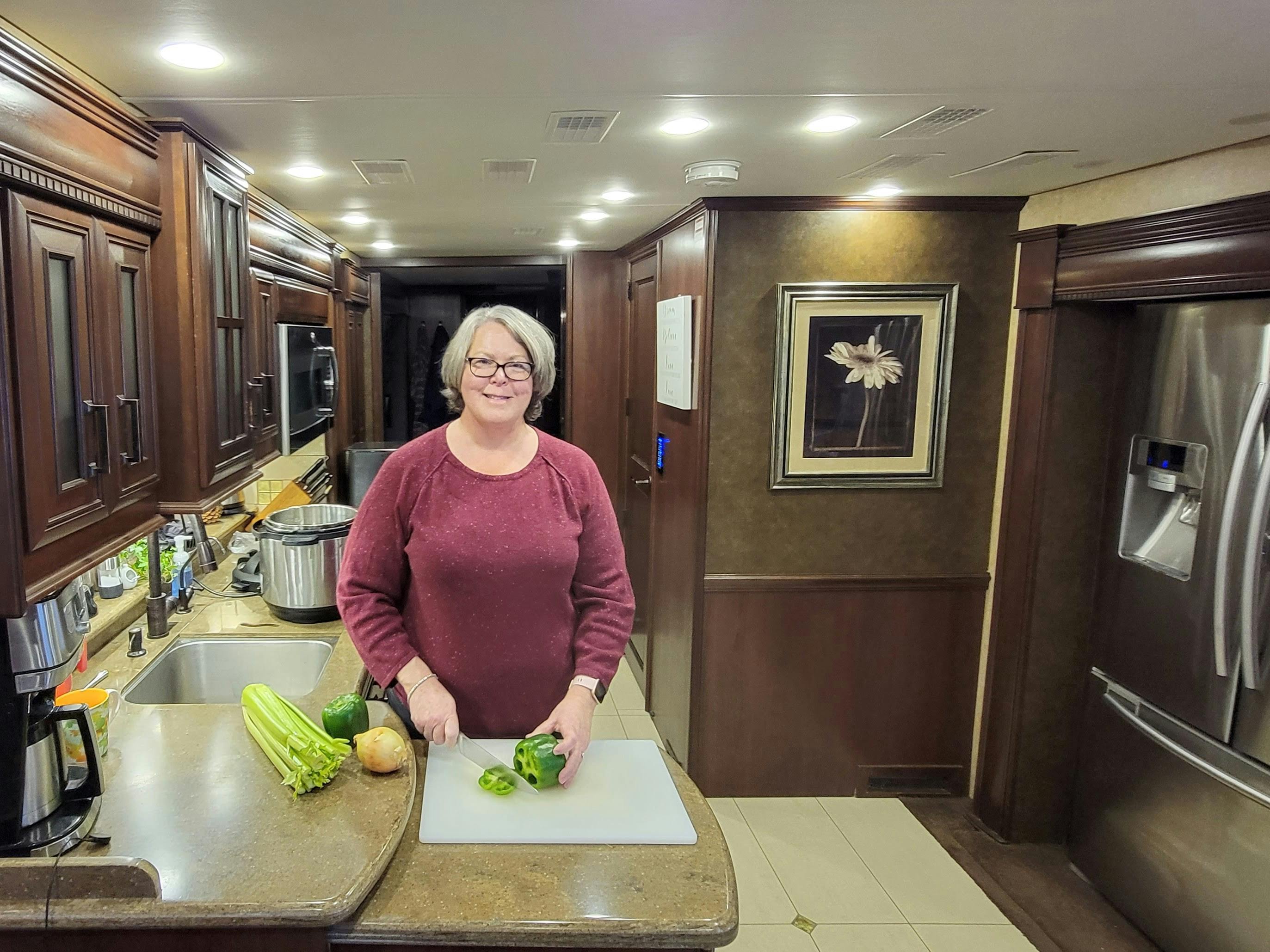 ANNE KLUMPP cutting a green pepper in the kitchen of her class a RV
