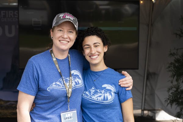 Two participants from First Descents, as organization that creates unforgettable outdoor experiences for young adults effected by cancer, smile together.