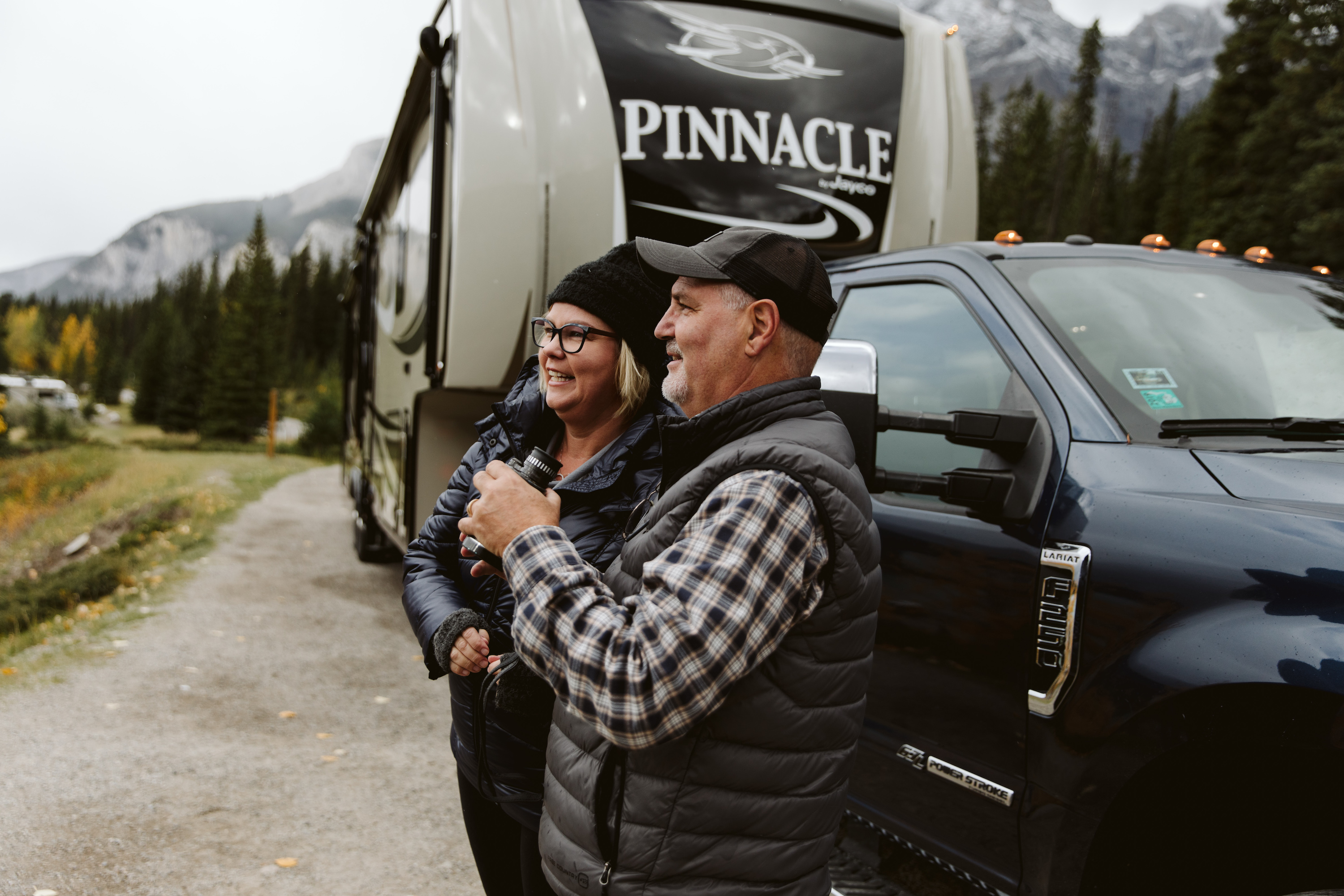 A couple using binoculars in front of an RV