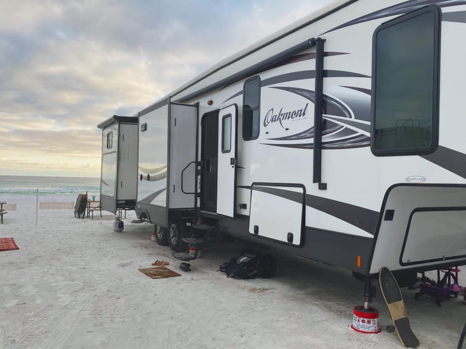 An RV trailer parked on the beach. 