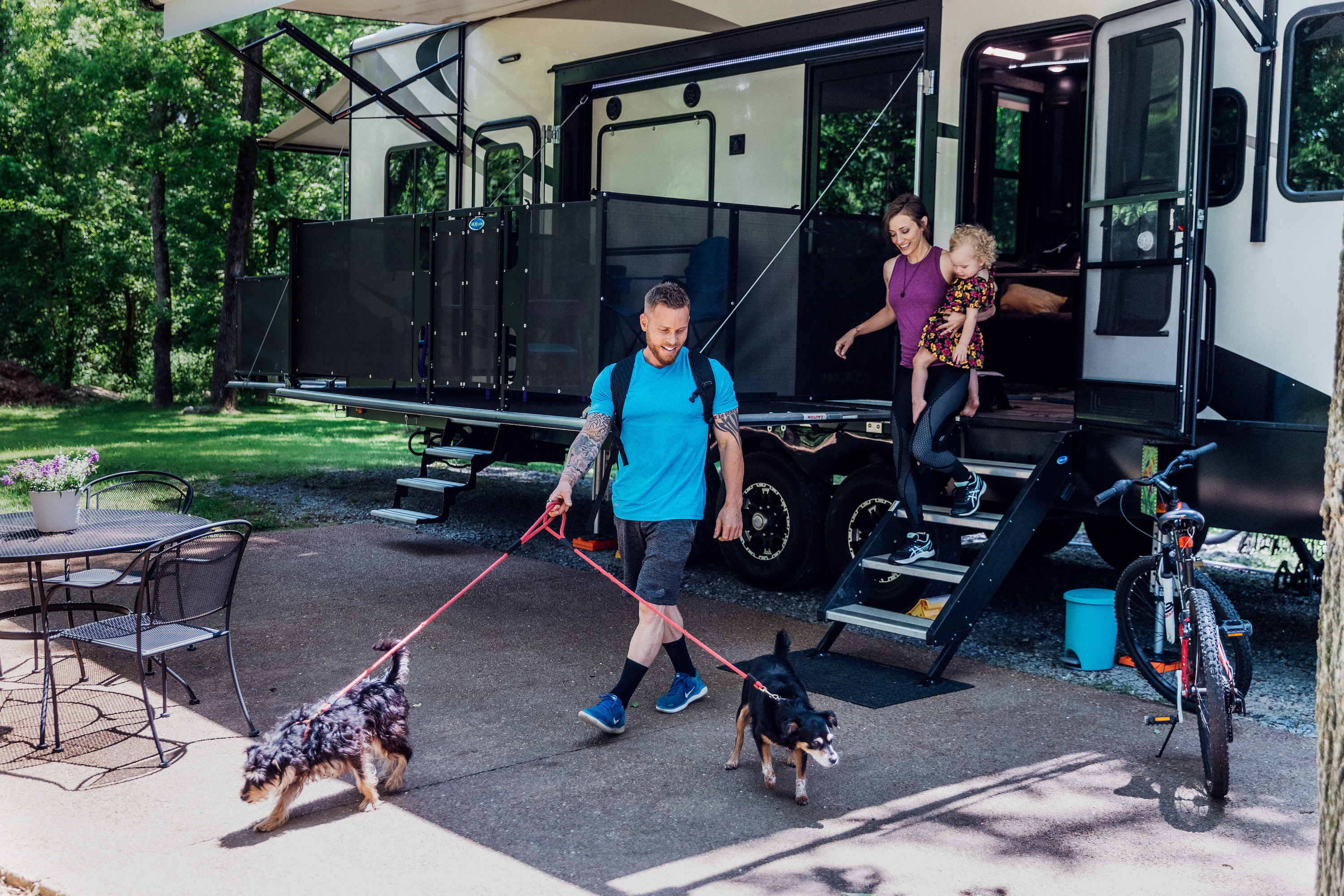 A man, woman and young child coming out of an RV to take two dogs for a walk. 