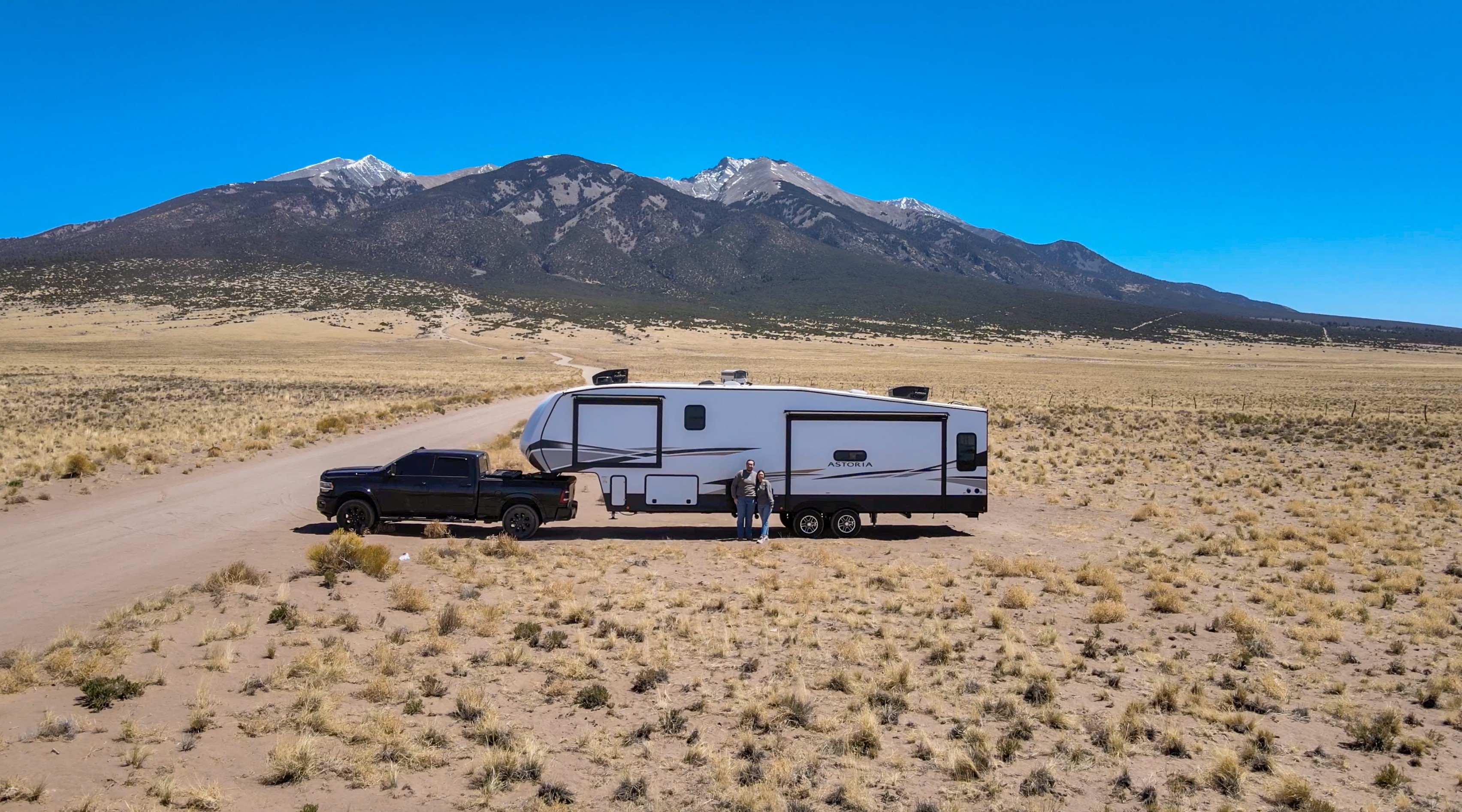 Bailey and Nicole Damberg pose in front of their Dutchmen Astoria Fifth Wheel in the desert.