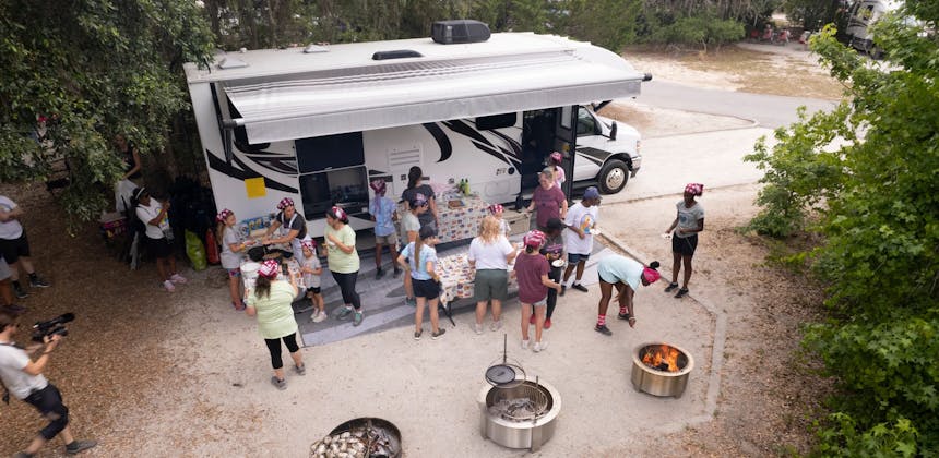 Girl Scouts cooking food outside on a Class C Motorhome