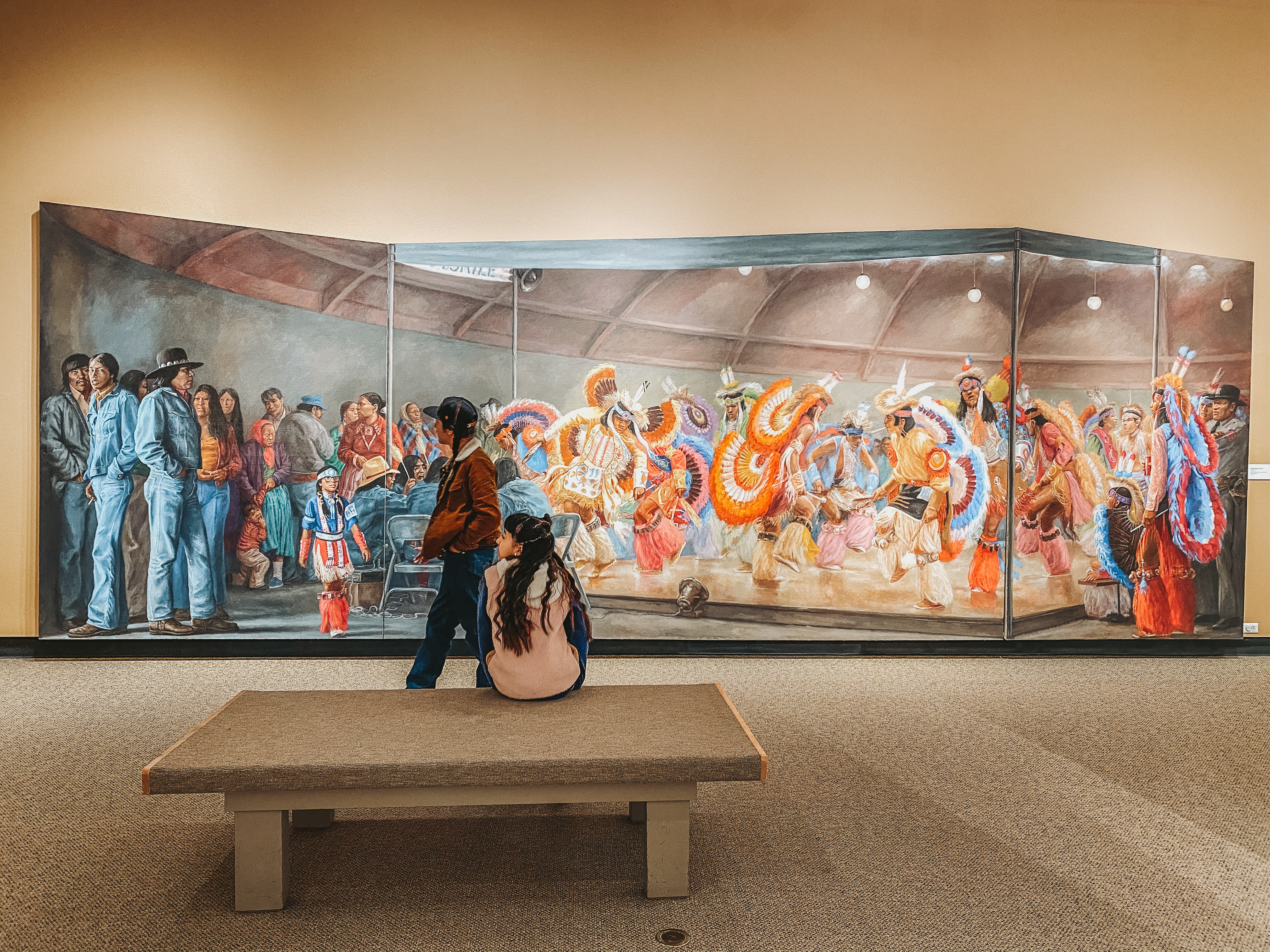 A wide shot of a museum mural depicting Native Americans in traditional and modern dress.