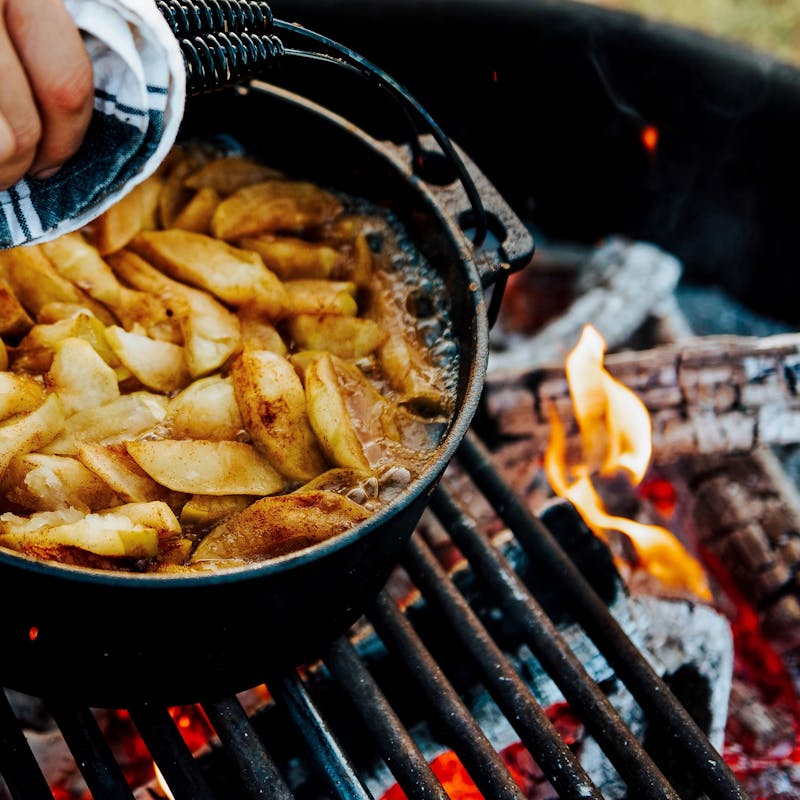 Apples baking in a dutch oven over a fire