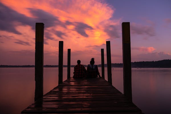 Chanel and Brittany Tate sitting on a dock watching the sunset.