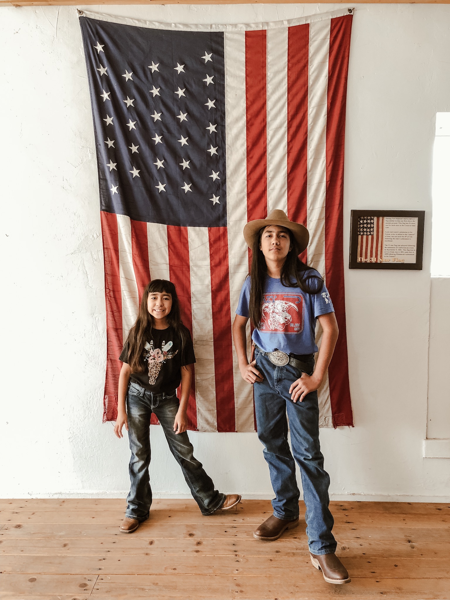 Two kids posed in front of an American flag display. 