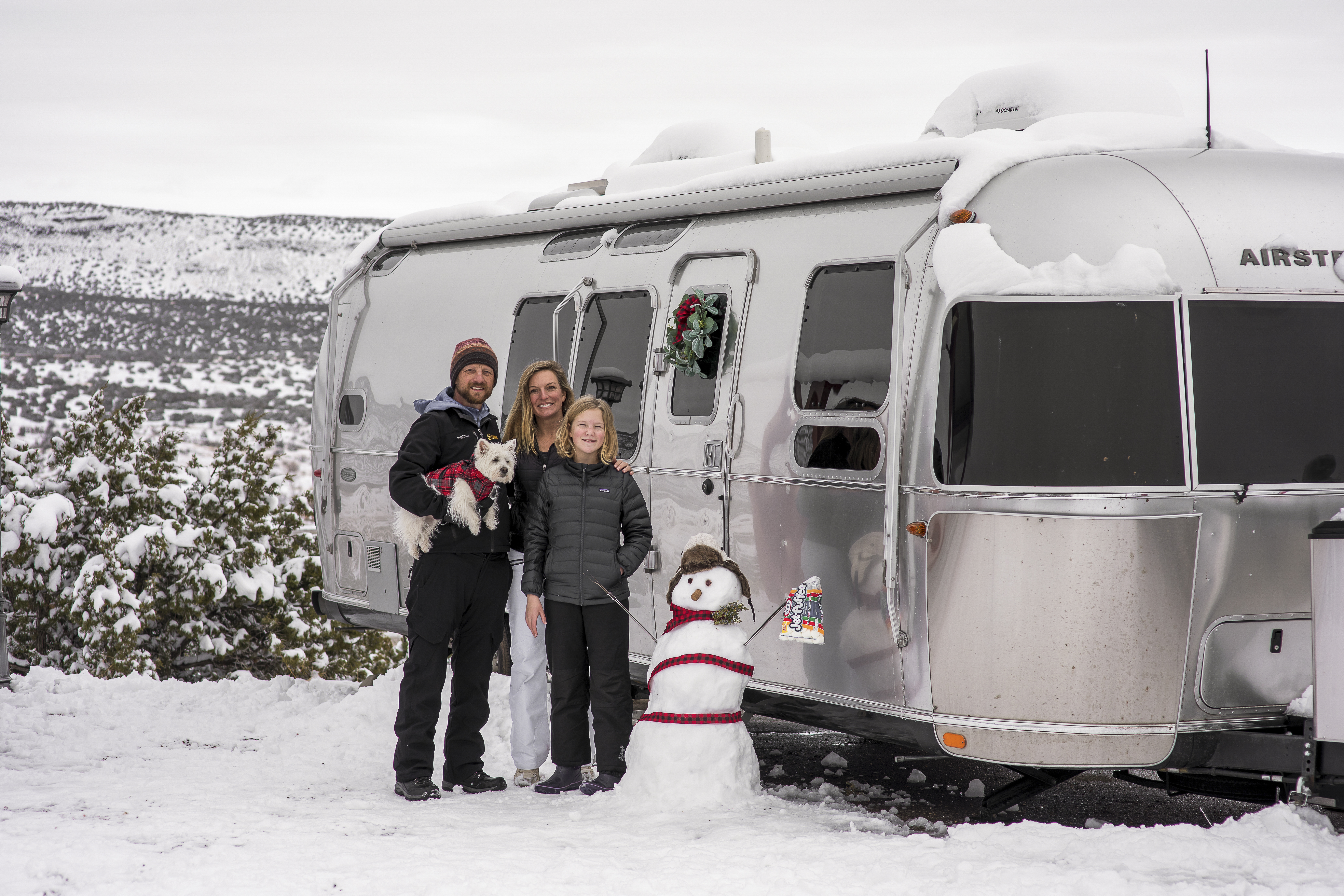 The Karen and Lenny Blue family posed outside their Airstream Flying Cloud with a snowman 