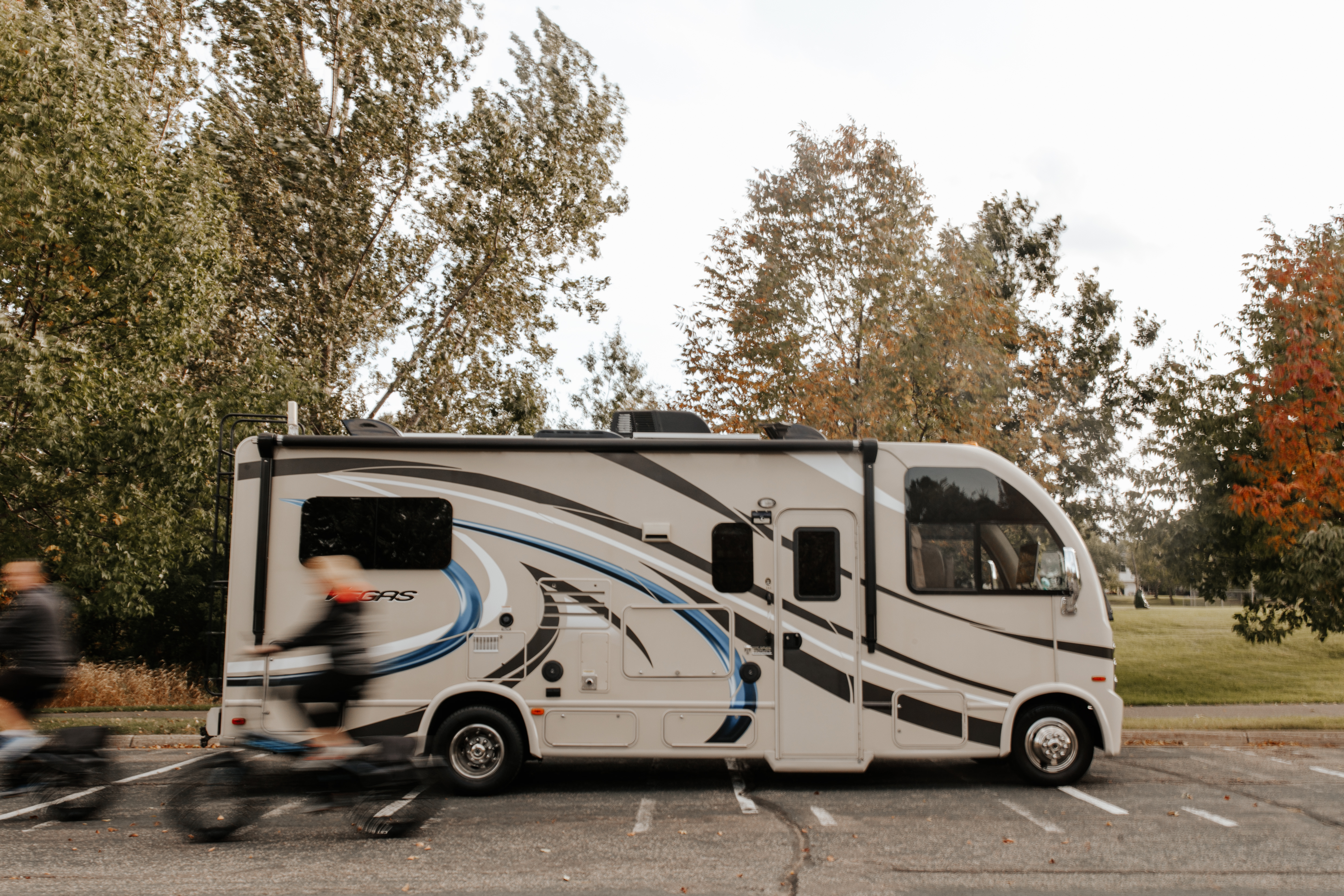 Dave and Kathy riding bikes in a whir past their parked RV. 