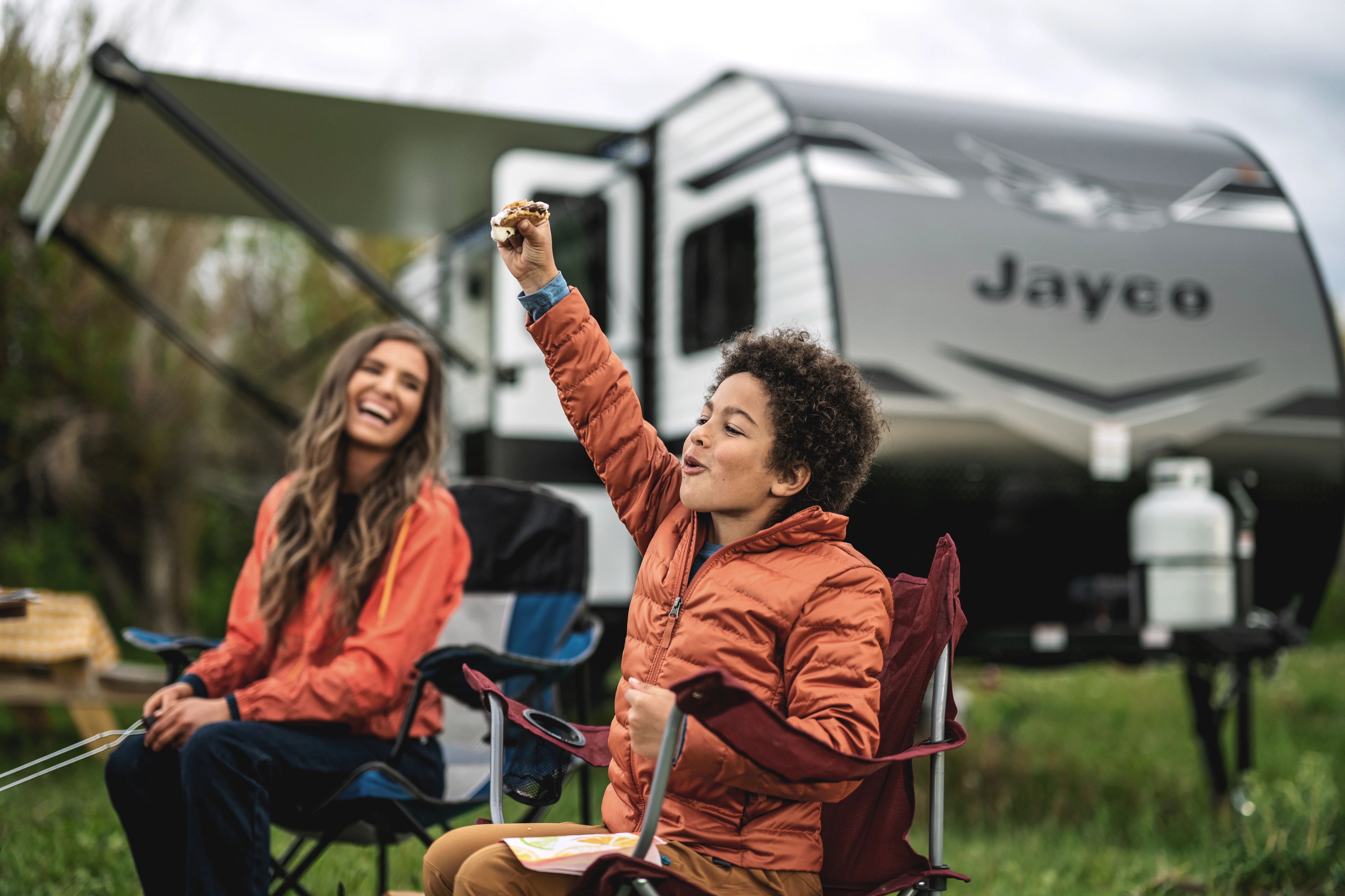 kid holding a smore in front of a jayco travel trailer