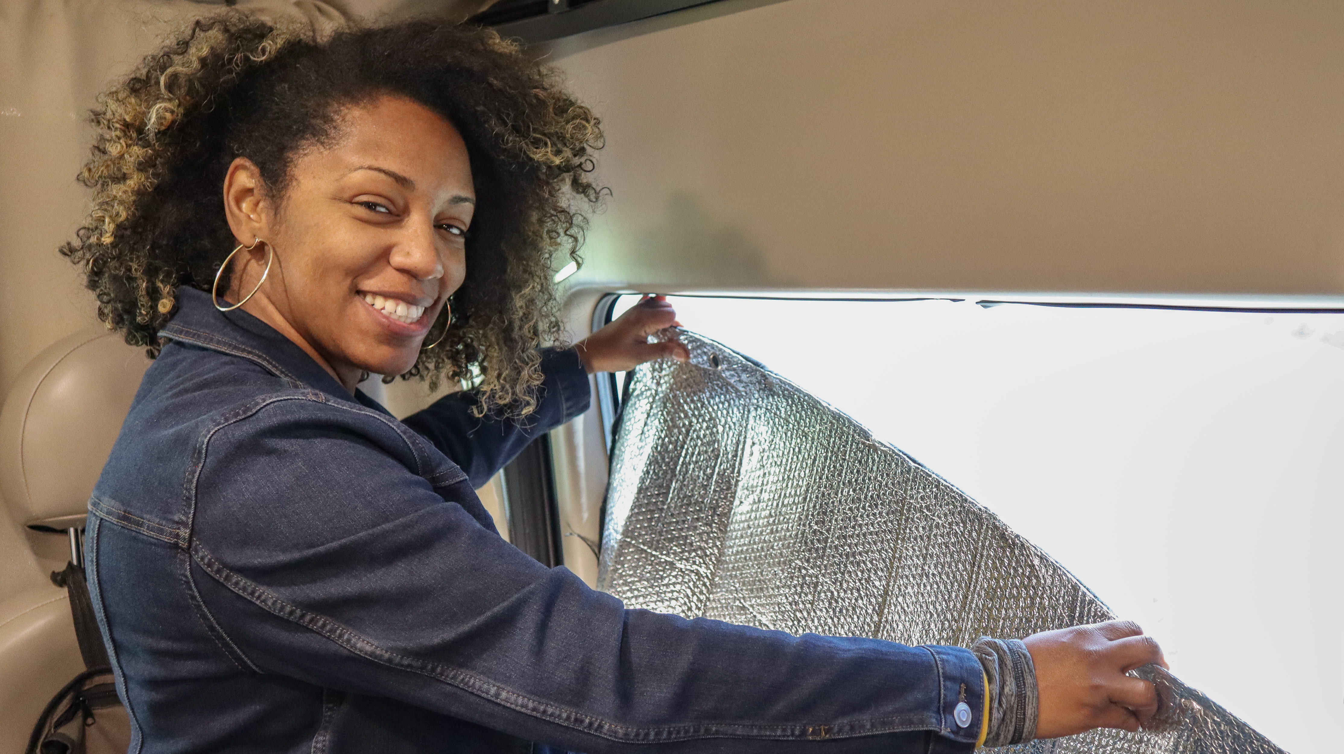 Rocio applying insulation to the window of her RV