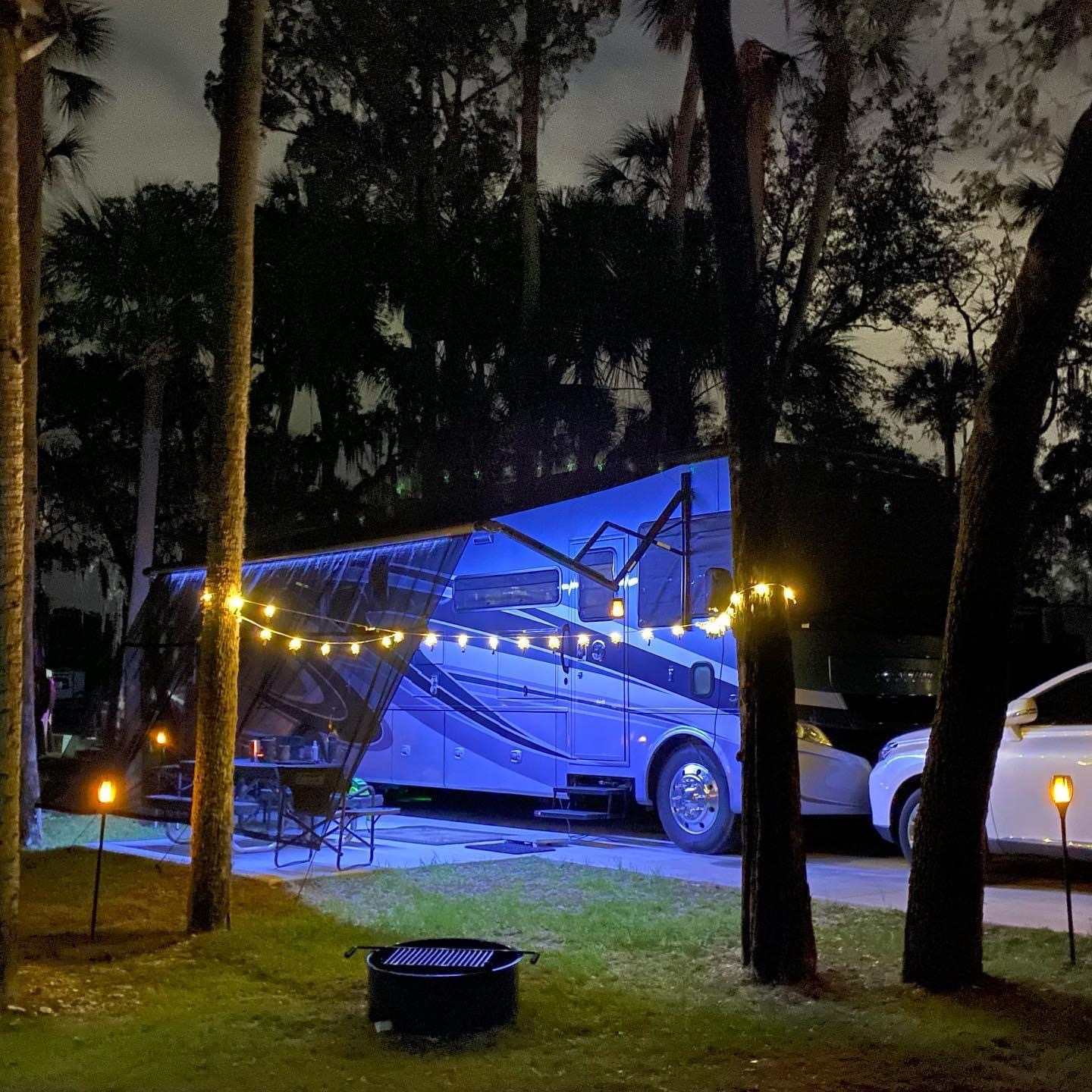 Michael and Tiffany Dunagan's Tiffin Allegro parked at a beach campsite with twinkle lights strung on trees.