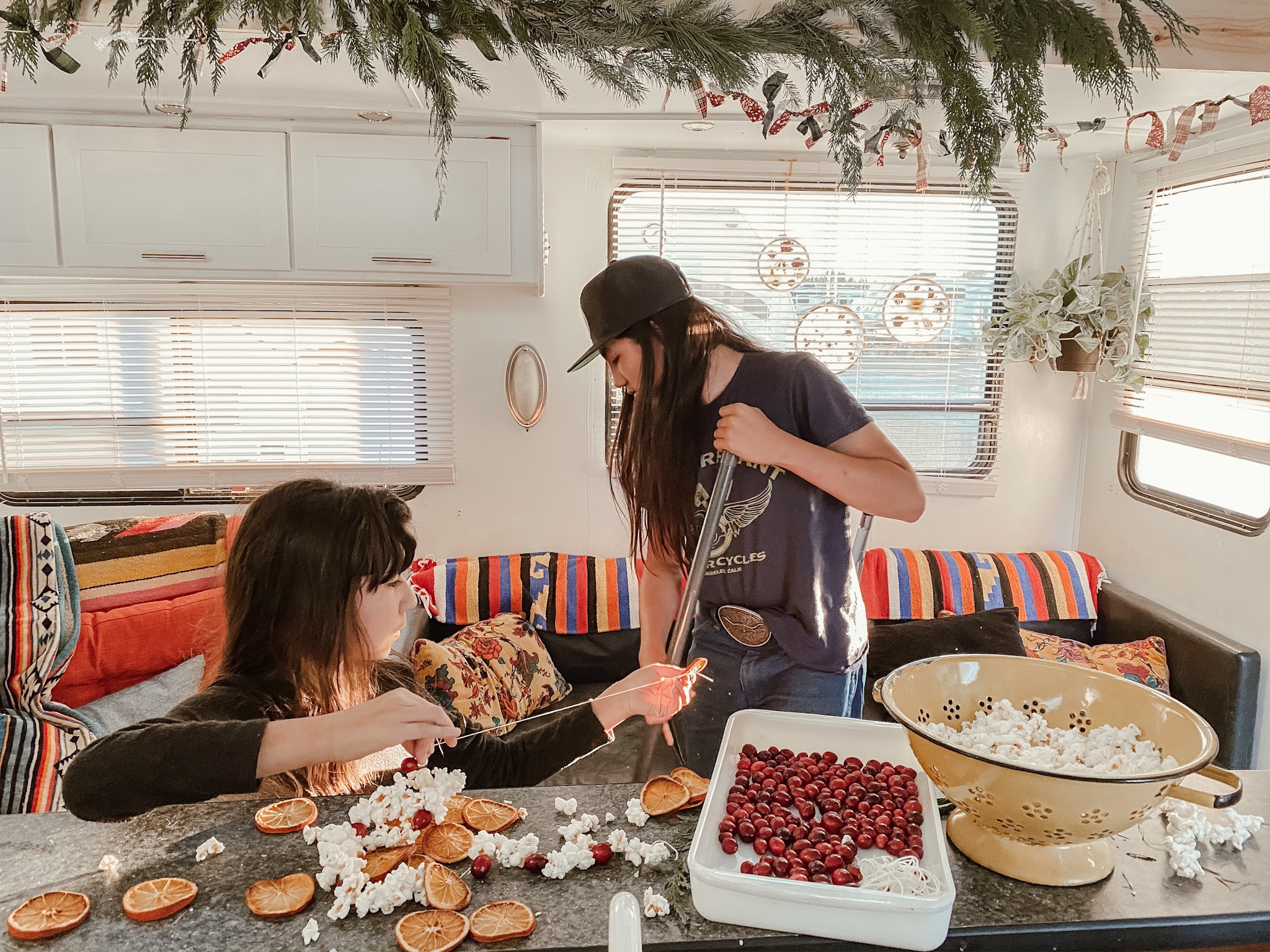 Two kids making Christmas garlands in an RV. 