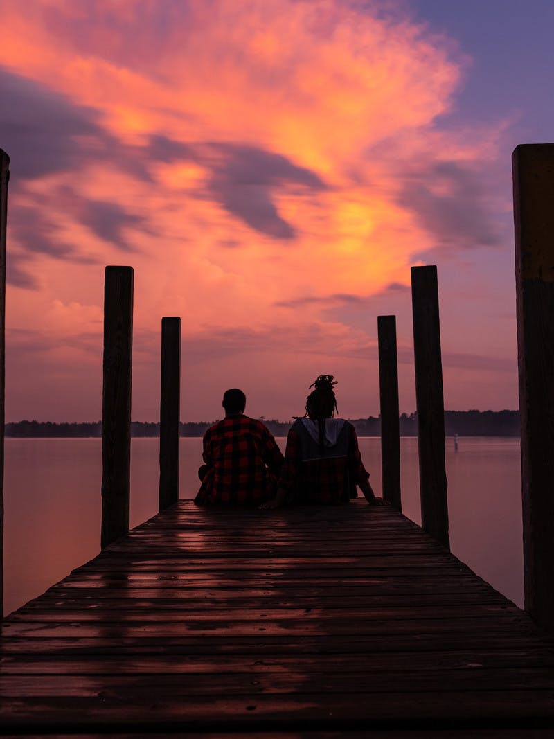 Chanel and Brittany Tate sitting on a dock watching the sunset. 