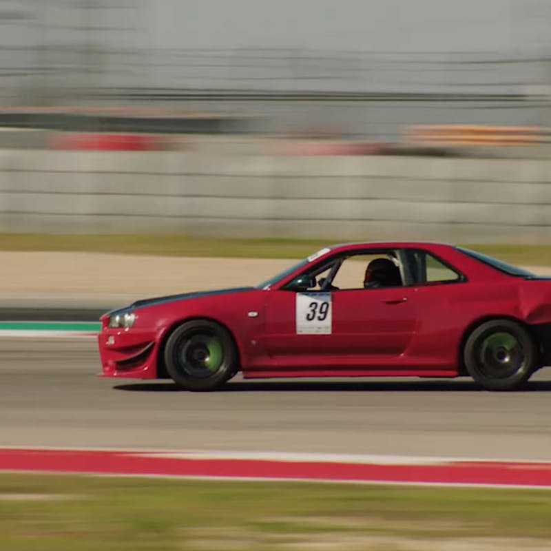 A red racecar drives quickly on the track.