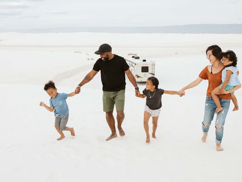 A family holds hands in front of an RV.