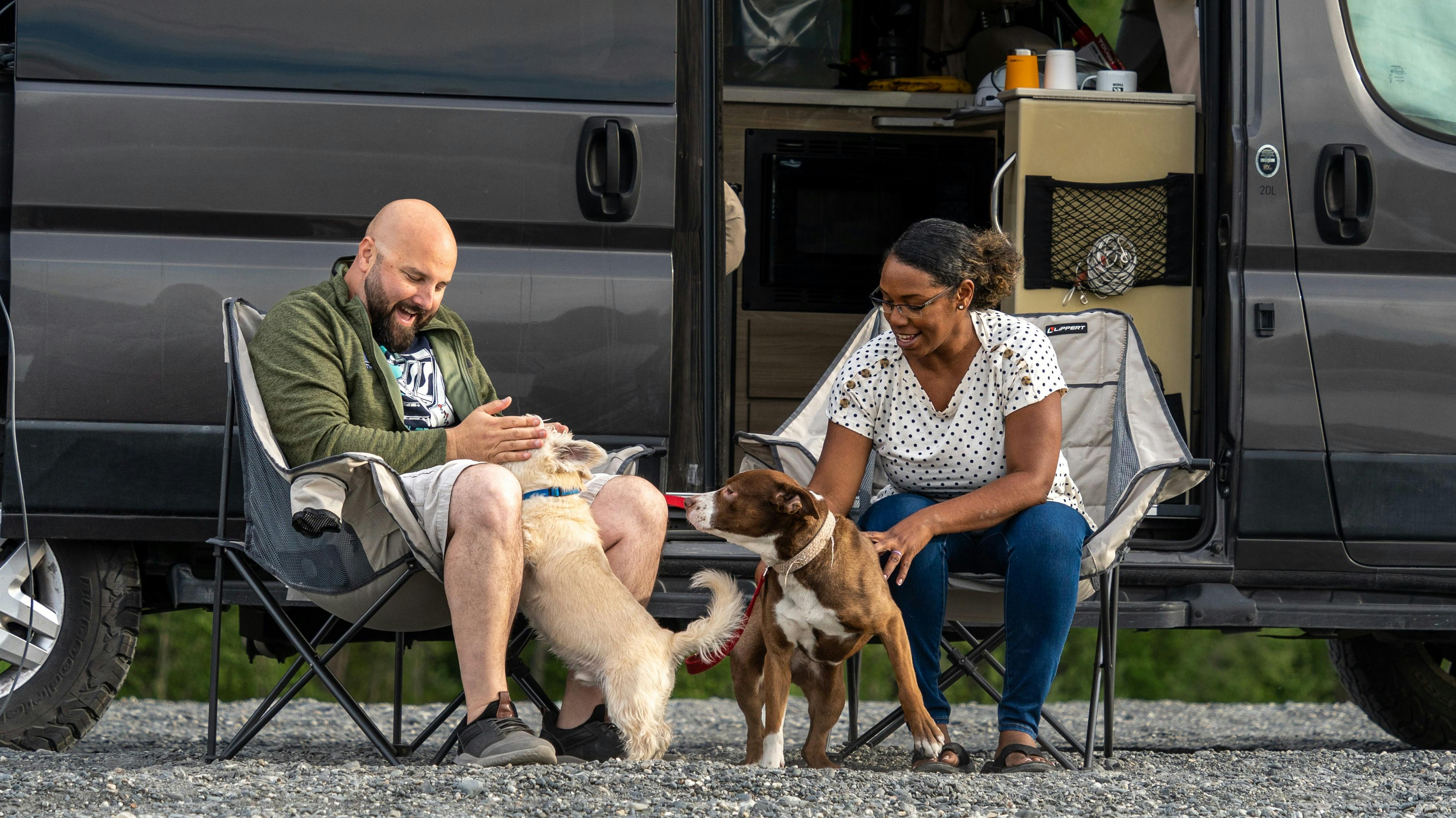 Gabe and Rocio petting their two dogs in front of their RV