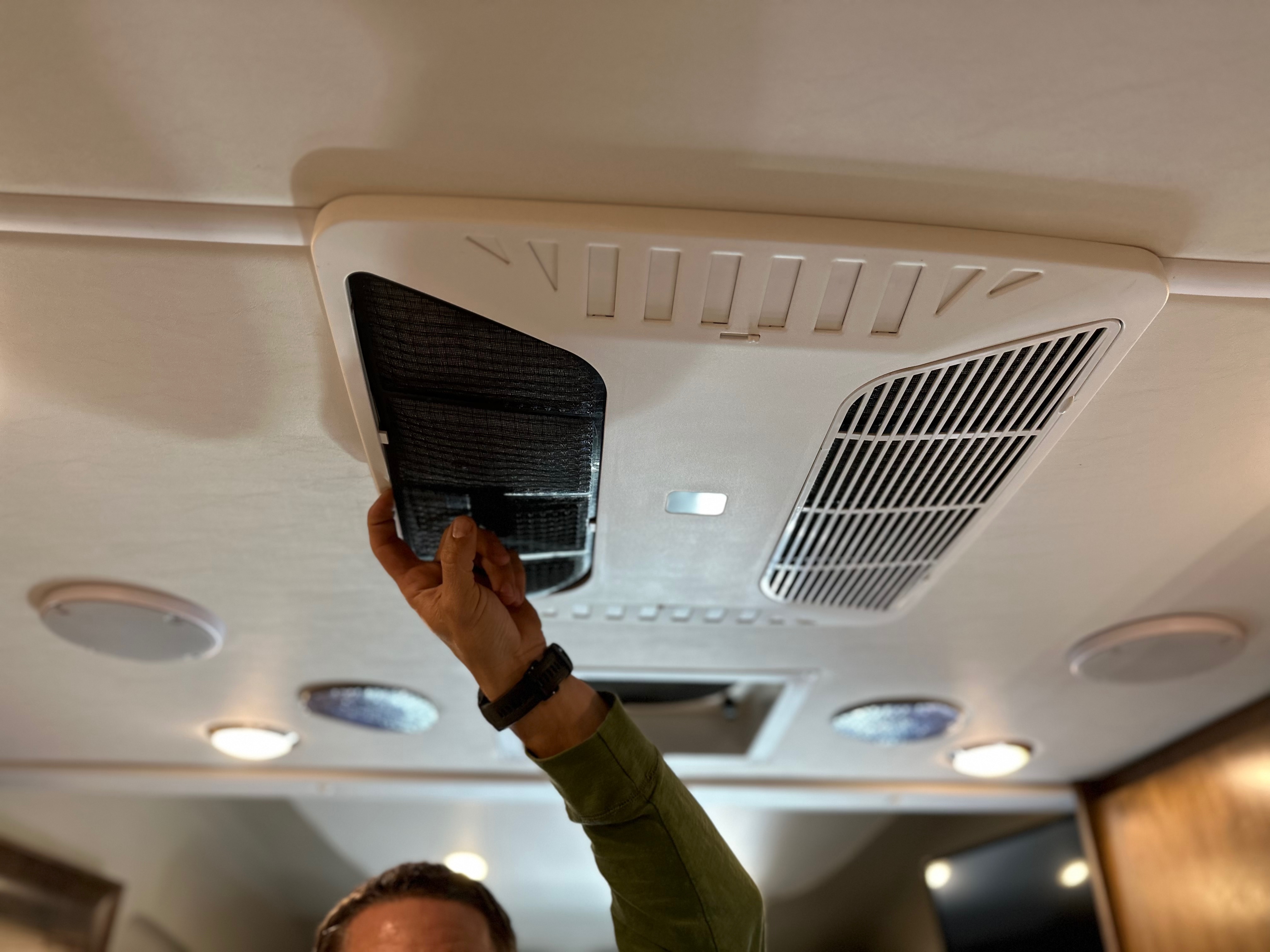 Dustin Bauer cleaning an air vent in his Tiffin Wayfarer