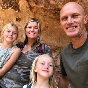 The Wells family, including husband and wife and their 2 girls, taking a selfie in the mountains.