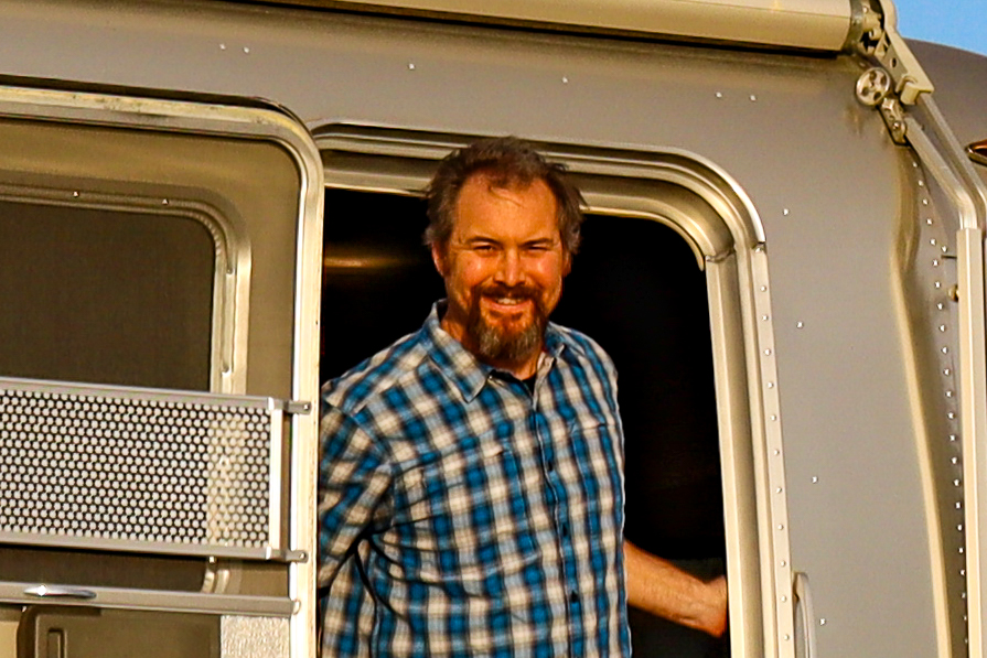 Greg Graham smiles while standing at the door of his Airstream.
