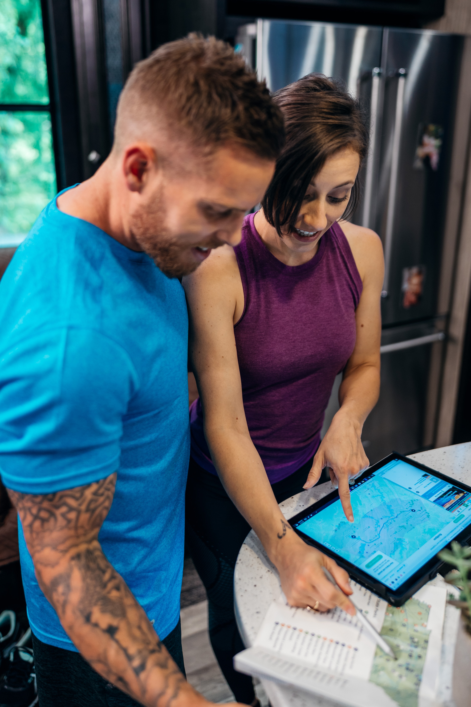 A man and a woman looking at an iPad and a map inside their RV.